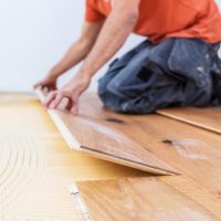 Un artisan pose un parquet dans une maison neuve moderne